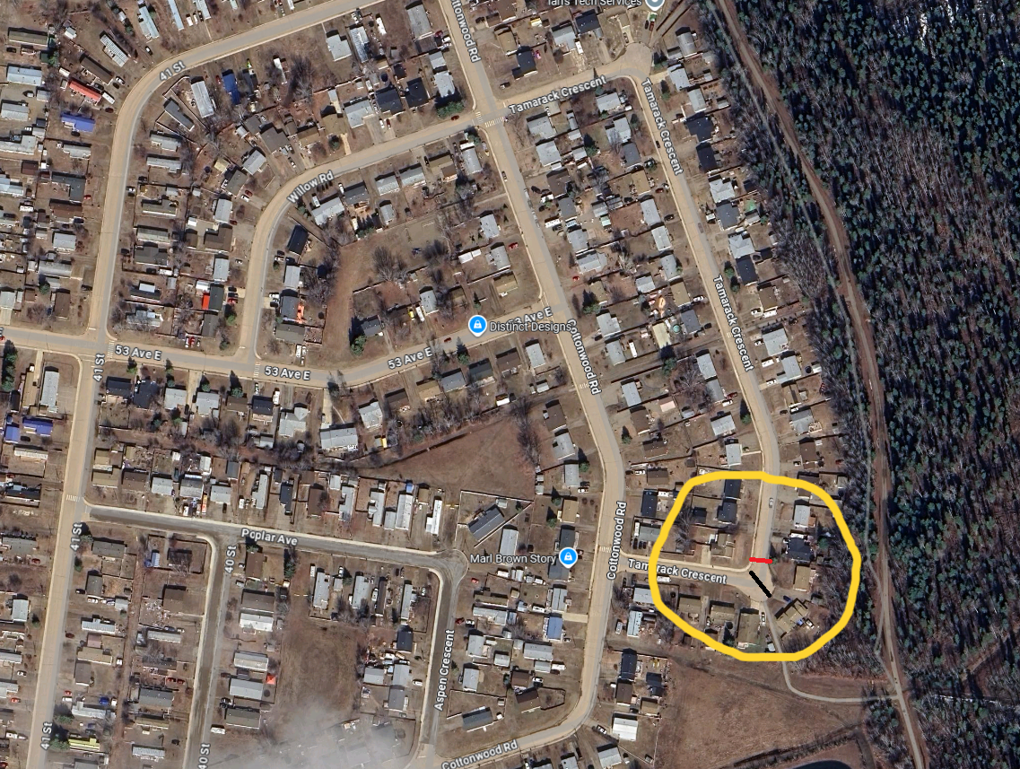 Aerial view of a town with roads, houses, and trees; area circled in yellow.