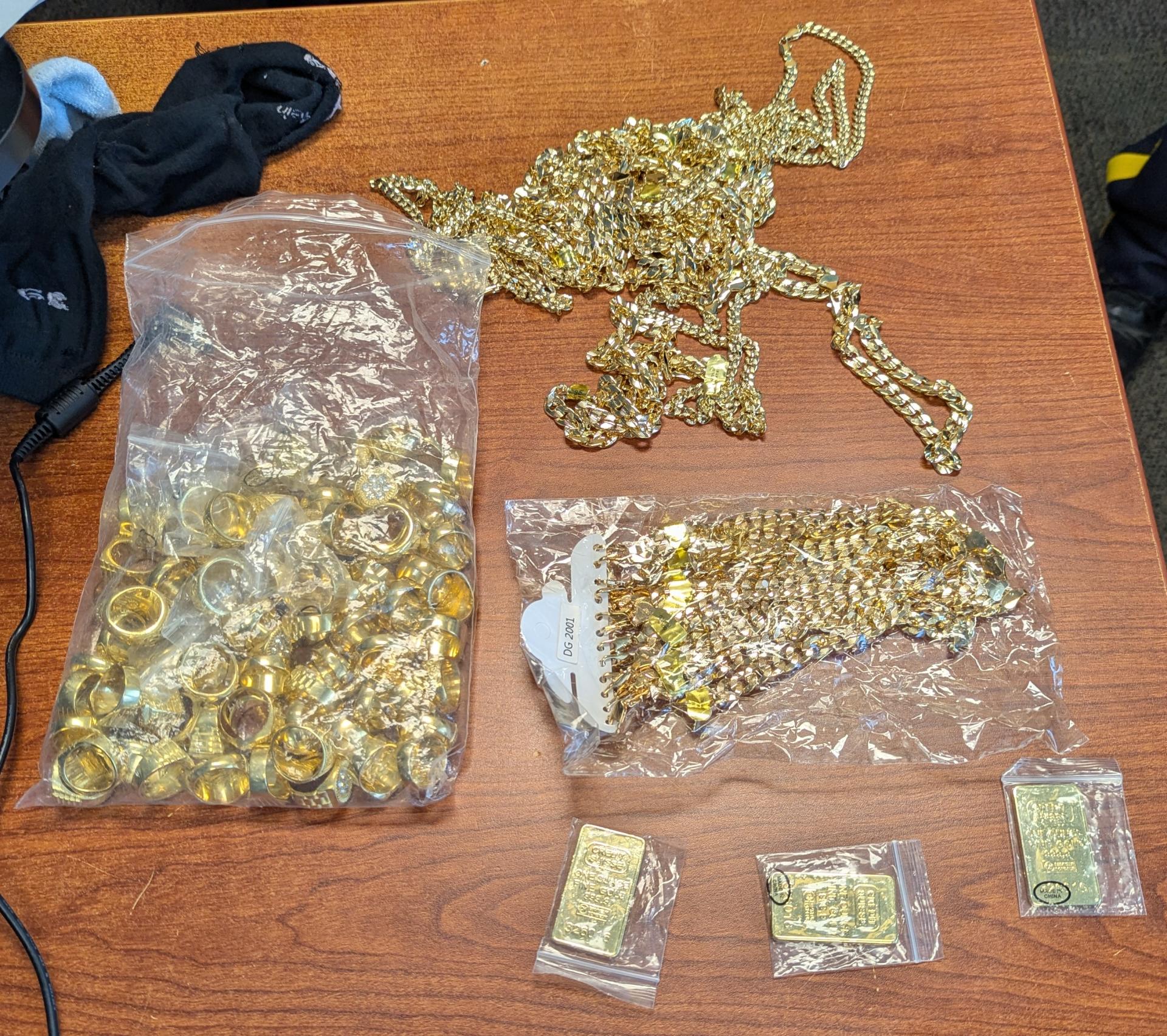 Gold-colored necklaces, rings, and trinkets on a wooden table.